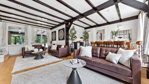 A spacious living room with a large brown leather sofa, a round coffee table, and a fireplace.