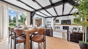A dining area with a wooden table and chairs, a fireplace, and a view of the garden.