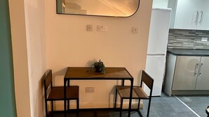 Eine kompakte Küche mit integriertem Kühlschrank, einem Holzespeisetisch mit vier Stühlen und einem wandmontierten Spiegel.