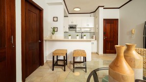 A modern kitchen with white cabinets, a microwave, and a small island with stools. - Bright & Modern 2BR/2BA Apartment Comfort & Style In cabarete (Cabarete)