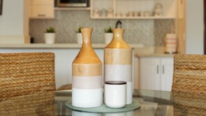 Two wooden vases on a glass table in a kitchen with white cabinets and a microwave. - Bright & Modern 2BR/2BA Apartment Comfort & Style In cabarete (Cabarete)
