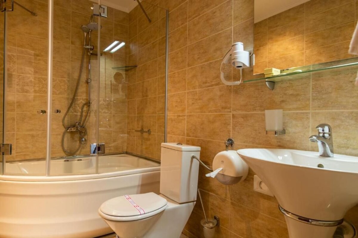 A modern bathroom with a glass-enclosed shower, a white toilet, and a freestanding sink.