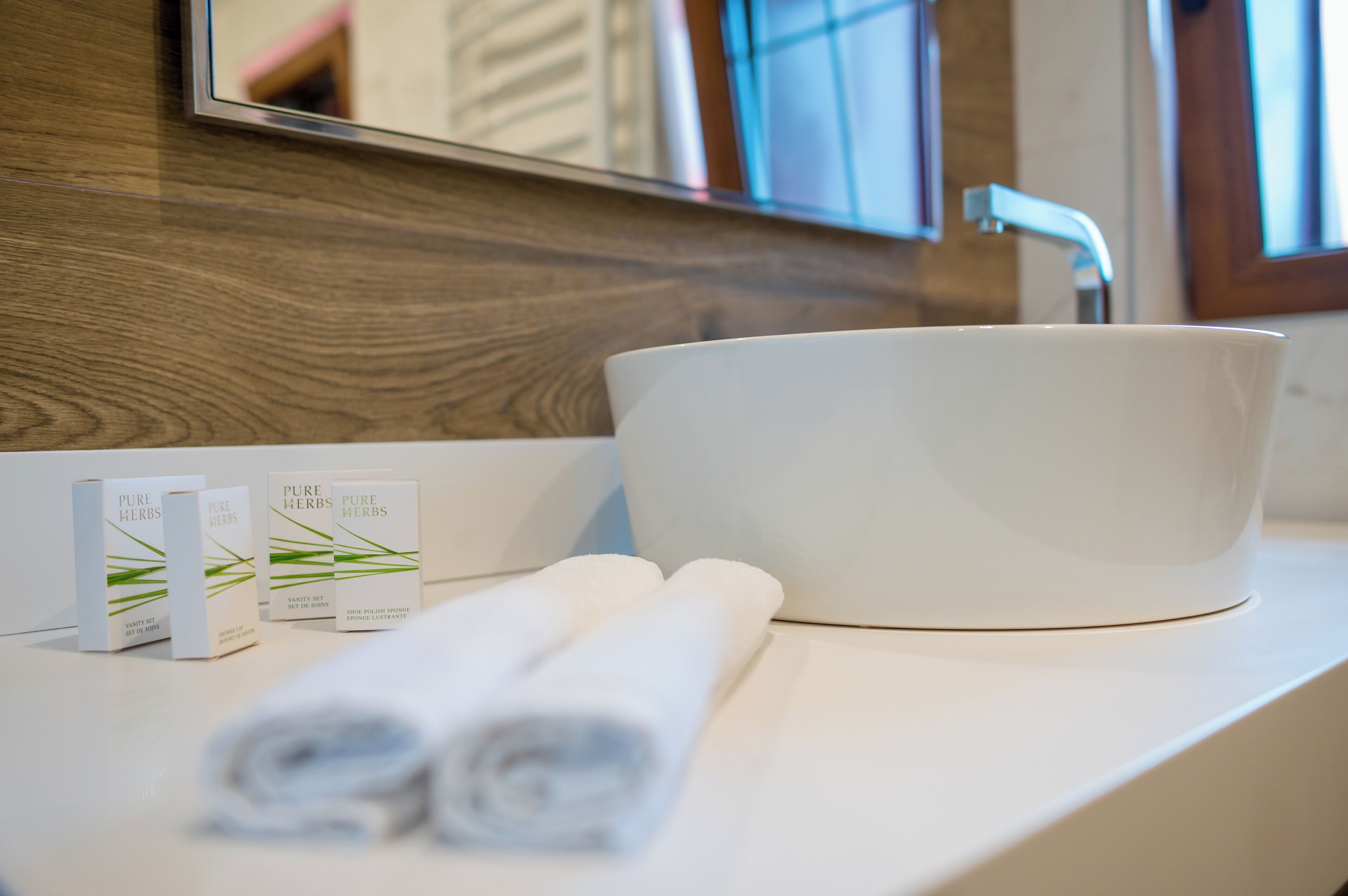 A white sink with a modern faucet, a mirror above it, and a wooden wall.