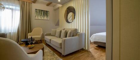 Una habitación de hotel moderna con sofá, una silla, una mesita con un vaso y una cama.