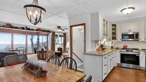 A spacious kitchen with a wooden dining table, white cabinetry, and a built-in oven. - Escape to the mountains in this cozy yet luxurious 3-bedroom, 2-bath retreat tucked away in the gated Bent Tree community of Jasper, GA! (Jasper)