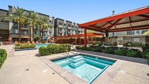 A hotel pool area with a rectangular pool, lounge chairs, palm trees, and a covered seating area. - Olympus loft 2. Lovely apartment with fitness room and AC in Chandler (Chandler)