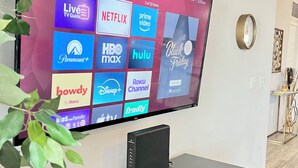 A TCL Roku TV mounted on a wall displaying various streaming services. - Olympus loft 2. Lovely apartment with fitness room and AC in Chandler (Chandler)