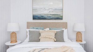 Ein Schlafzimmer mit einem Bett, zwei Nachttischlampen und einem Wandbild.