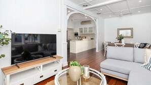 Ein modernes Wohnzimmer mit Fernseher, Sofa und Essbereich.
