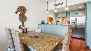 A kitchen with a granite countertop, a stainless steel refrigerator, and a blue island. - Salty's Six Palms 4A (Santa Rosa Beach)
