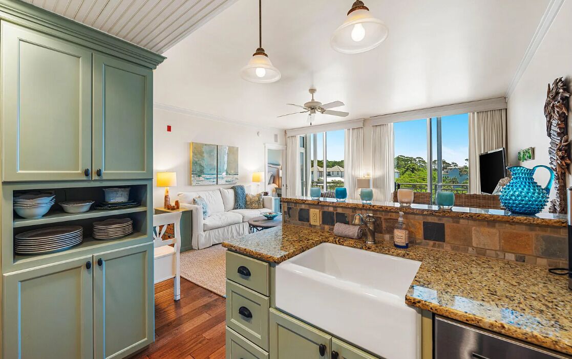 A modern kitchen with granite countertops, a built-in sink, and a dining area with a white table and chairs.