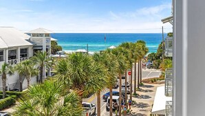 A coastal street with a view of the ocean, palm trees, and buildings. - Salty's Six Palms 4A (Santa Rosa Beach)