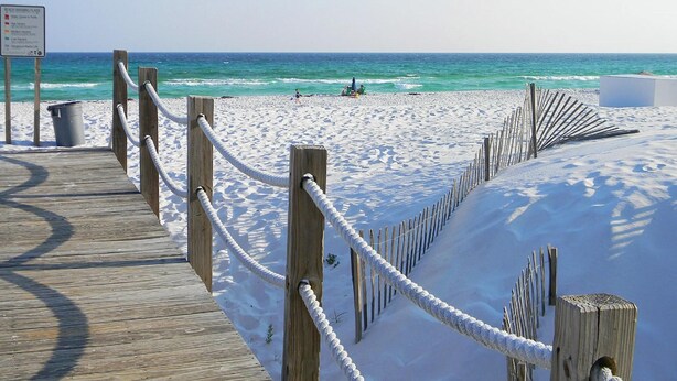 Una passerella in legno che conduce a una spiaggia sabbiosa con vista libera sull'oceano.
