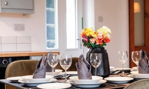 A dining table set with plates, glasses, and a vase of flowers.