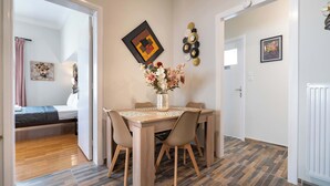 A dining area with a wooden table and chairs, a vase with flowers, and artwork on the walls.