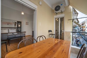 A dining area with a wooden table and chairs, a bench, and a balcony with a railing. - Attiki Haven – 4BR Stay • Steps from Metro by ΜΡS (Athina)