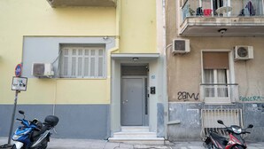 A building with a gray door, air conditioning units, and a balcony with laundry hanging.