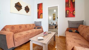 A modern living room with two sofas, a coffee table, and abstract wall art.