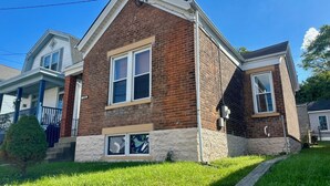 A two-story brick house with a front porch and a small front yard.