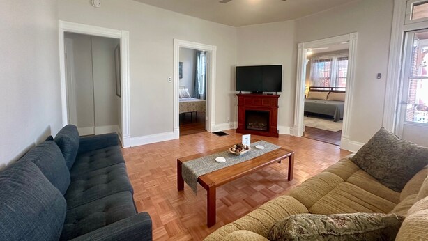 A living room with a wooden floor, a television, a fireplace, and two sofas.