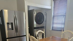 A kitchen with a stainless steel refrigerator, a built-in oven, and a dining table with four white chairs.