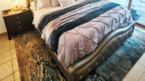 Une chambre à coucher avec un lit, un ventilateur de plafond, des œuvres d’art accrochées au mur et une vue par la fenêtre.