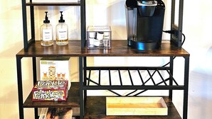 Un espace bar avec des étagères où sont rangées des tasses à café, une machine à café et des jeux de société.