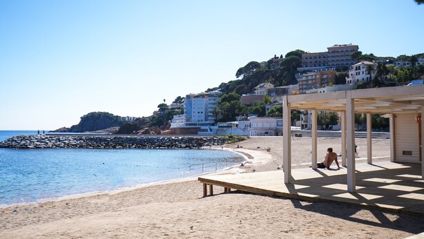 A beach with a wooden deck and a building in the background. - SJ7 Aparthotel (Sant Feliu de Guíxols)