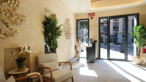 A hotel lobby with a reception desk, seating area, and large windows. - SJ7 Aparthotel (Sant Feliu de Guíxols)