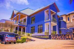 A multi-story building with balconies and a car parked in front. - New G&M Stays Kigali (Kigali)