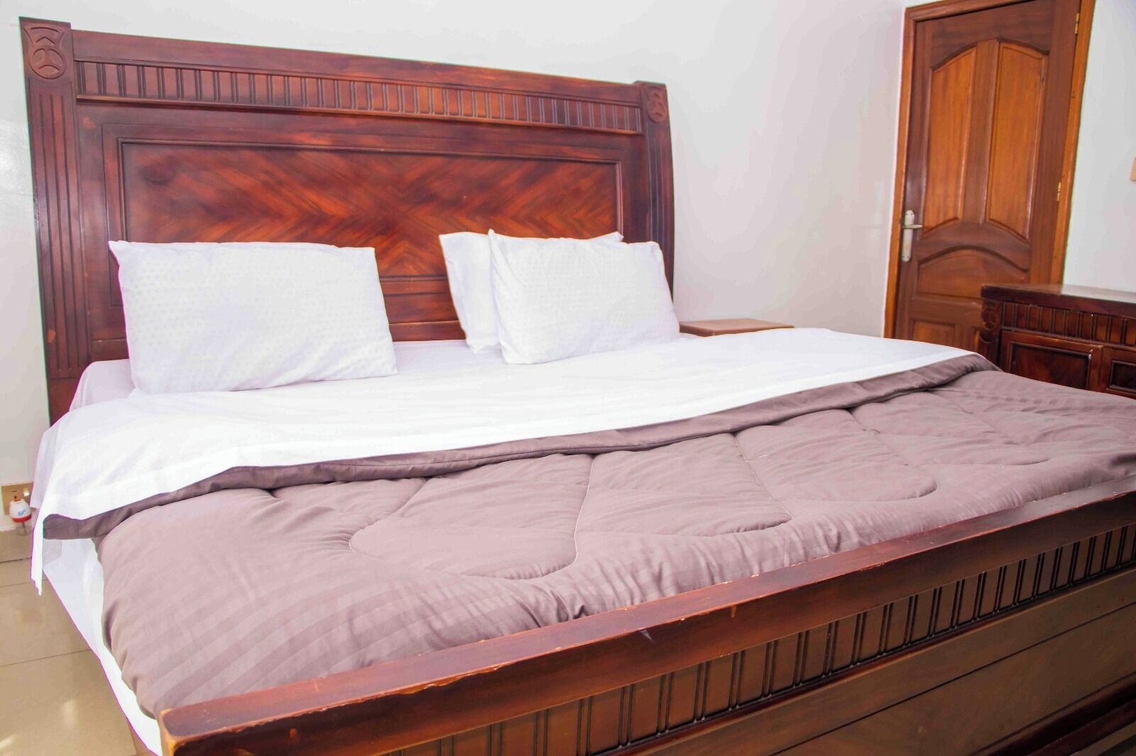 A wooden bed with a headboard, white pillows, and a brown blanket.