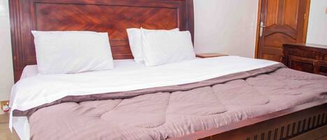 A wooden bed with a headboard, white pillows, and a brown blanket.