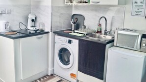 Una cucina compatta con lavatrice, forno a microonde e lavello.