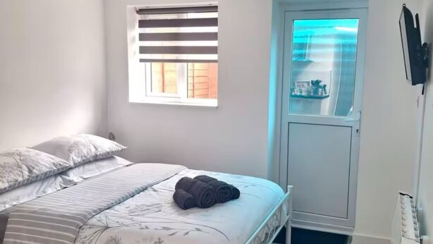 Una camera da letto con un letto, una finestra, una porta e un termosifone.