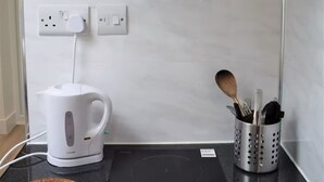 Una cucina moderna con una cappa in vetro, un bollitore bianco e un portacorrente.