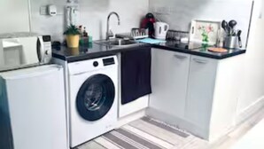 Ett kompakt kök med tvättmaskin, mikrovågsugn och diskho.