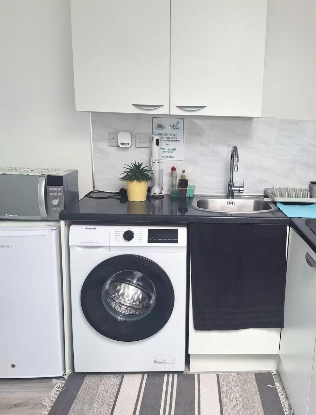 Una cocina compacta con lavadora, microondas y lavaplatos.