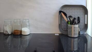 A kitchen with a glass hood, a black countertop, and jars of spices.