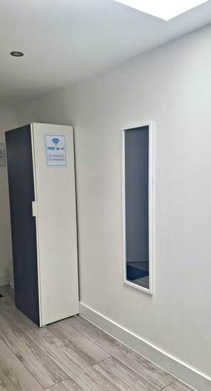 A room with a door marked 'FREE Wi-Fi', a small window, and a wooden floor. - Delightful studio apartment close to Heathrow (Northolt)
