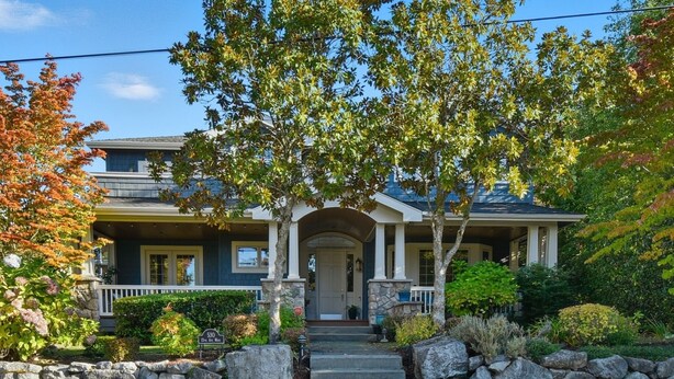 A two-story house with a stone facade, a front porch with columns, and a well-maintained garden. - Private Guest Suite in Beautiful Kirkland, West of Market neighborhood. (Kirkland)