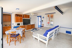 Un espace de vie compact comprenant une kitchenette, un coin repas et un canapé-lit.