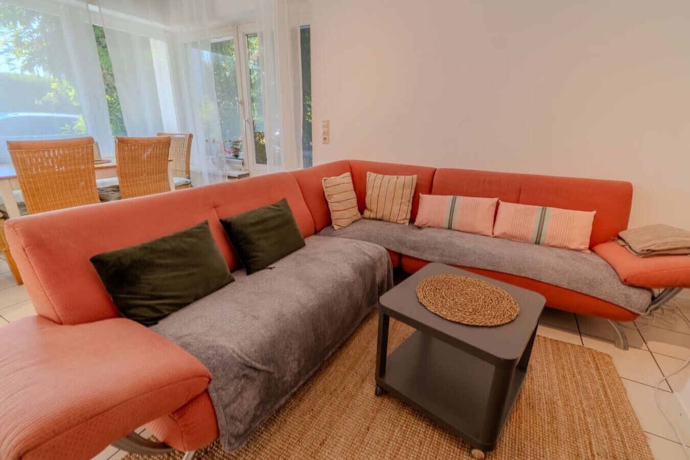A modern living room with a sectional sofa, a small coffee table, and wicker chairs.