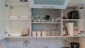 Et køkken med åbne skabe, der viser tallerkener, glas og køkkenudstyr.