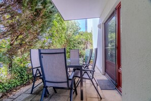 Une terrasse extérieure avec une table et des chaises, entourée de verdure.