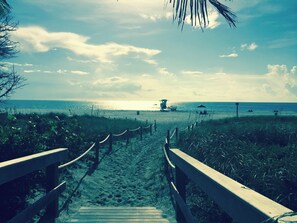 A wooden pathway leading to a beach with a lifeguard tower and a covered area. - 2-bedroom condo in  Pompano Beach with views of the Intracoastal and Ocean (Pompano Beach)