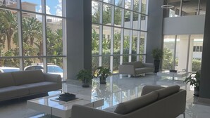 Un hall d’entrée spacieux au design moderne, comprenant un grand canapé, une table basse et des plantes en pot.