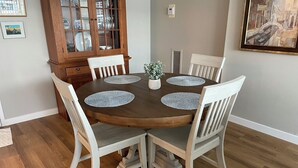Une table à manger avec quatre chaises, un buffet en bois avec des portes en verre et une petite plante posée sur la table.