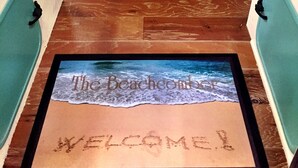 Un couloir avec un paillasson représentant une scène de plage et portant le mot « BIENVENUE ».