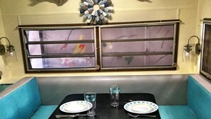 Un intérieur de camping-car compact doté d’un coin repas comprenant une table et deux banquettes bleues rembourrées.