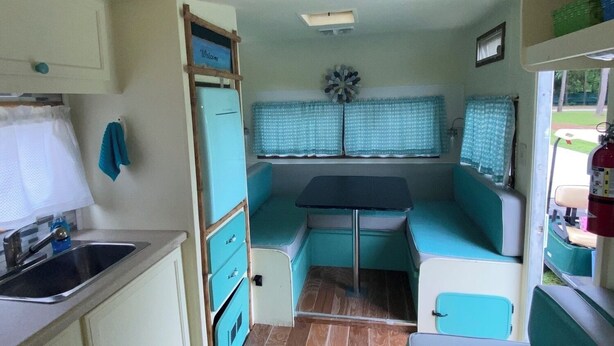 Une cuisine compacte pour camping-car, comprenant un évier, des placards et un petit coin repas.